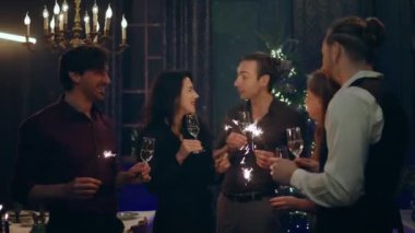 Noel ağacının yanında tartıştıkları ve ellerinde şampanya bardakları ve pırıltılarıyla Noel 'i birlikte kutlayan çok çekici ve güzel insanlar. 4k