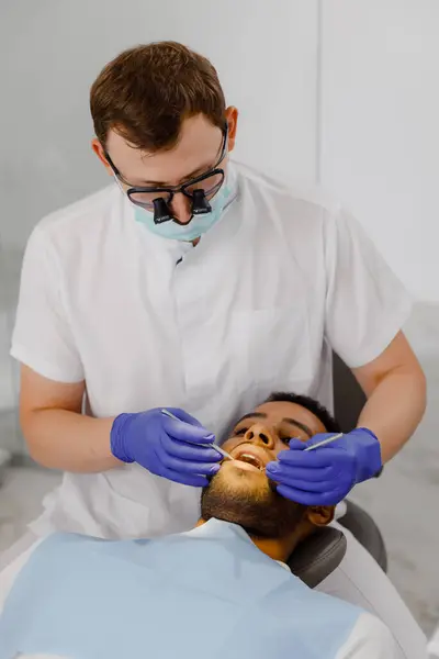 牙科诊所的保健理念使牙科医生在现代宽敞的诊所中仔细工作 — 图库照片