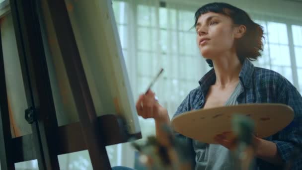 一个矮小的艺术家与短发绘画的一些非常时髦和现代的东西 她的画笔在她前面的帆布上 — 图库视频影像
