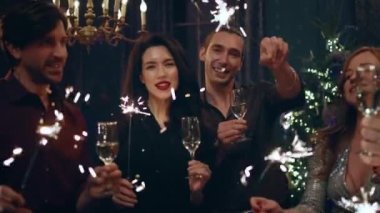 Kocaman gülümseyen güzel kadınlar ve çok yakışıklı erkekler kameranın önünde poz veriyor ve ellerinde şampanya kadehleri ve pırıltılarıyla Noel 'i ya da yeni yılı kutluyor. 4k