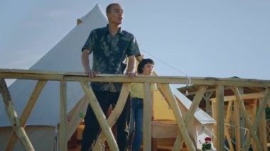 Çok iyi görünümlü bir grup insan küçük balkona giden bir çadırdan çıkıyorlar ve birlikte doğaya çok mutlu bir şekilde bakıyorlar. 4k