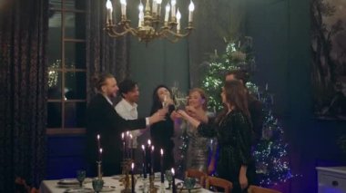 Noel gecesi kavramı çok iyi görünümlü yetişkinler Noel ağacının yanında durdukları Noel 'i kutluyor ve yemeğe başlamadan önce şampanyayla şerefe diliyor. 4k