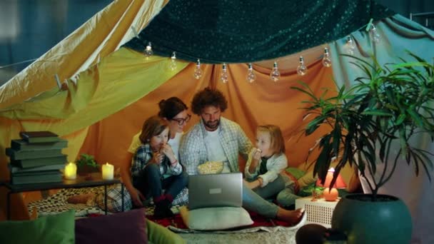 两个可爱漂亮的男孩和他们的父母坐在孩子们房间里手工搭建的帐篷里 一边吃爆米花 一边在笔记本电脑上看电影 这真是令人惊奇的家庭时光 — 图库视频影像