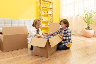 Aile yeni eve taşınırken karton kutularda oynayan iki çocuğun portresi. Aile
