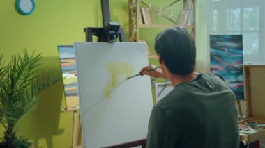 Sanat atölyesindeki sanat eğitimi kavramı ressam paletten yağ rengini alır ve fırçayla tuvali boyamaya başlar. 4k