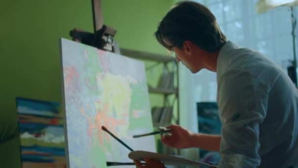 在艺术工作室里 有魅力的艺术家在画布上创作他的新画 他从调色板艺术教育的概念中添加了一些油画色彩 — 图库视频影像