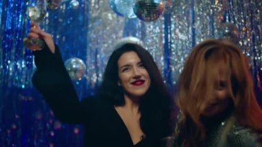 Çok güzel ve heyecanlı bir bayan dans ediyor ve büyük bir gülümsemeyle Noel 'i ya da yeni yılı kutluyor ellerinde şampanya bardakları tutuyorlar. 4k