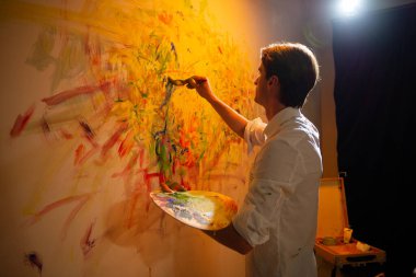 Sanat stüdyosu ressamı çağdaş resim çizerken parmaklarını kullanır ve resme biraz yağ katar. Boya