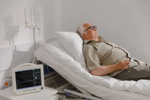 In the hospital the patient old man patient resting in bed eating for a checkup he wearing the heart rate monitor pulse oximeter showing pulse. Hospital