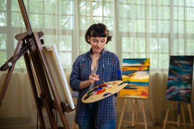 katta oturan ve Sanat Atölyesi resim çizim güzel genç kadın ressam.