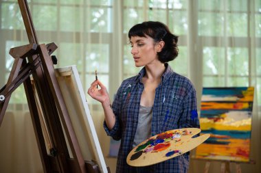 Yaratıcılığını hayata geçiriyor. Resim stüdyosunda resim yapan bir kadın..