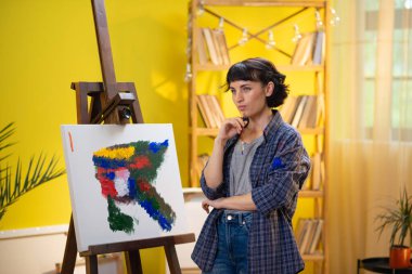 Sanatta birçok farklı fırça darbelerinde kullanılan farklı boya fırçalarıyla dolu büyük bir fincanın yakın çekimi ve bir ressam fincana fırça geri koyar. ressam