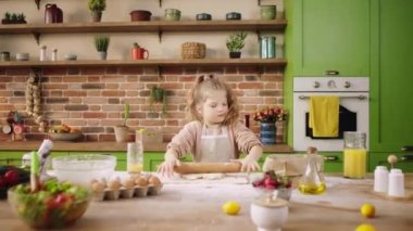 Çok çalışan güzel ve karizmatik küçük kız mutfak adasında çok çalışıyor tatlıya hamur hazırlıyor rulo alıyor ve mangırı modelliyor. ARRI Alexa Mini 'de çekilen
