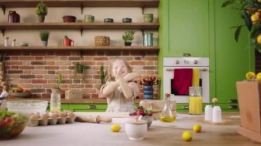 Kırsal mutfak adası güzel ve gülümseyen büyük çok heyecanlı küçük kız evdeki mutfak adasında tatlı hazırlarken dans ediyor..
