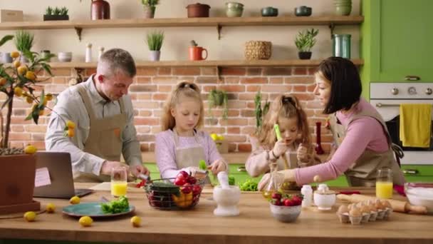 キッチンで2人の小さな女の子ママとパパが健康的なランチを用意し 野菜とサラダを一緒に作りました 4Kについて — ストック動画