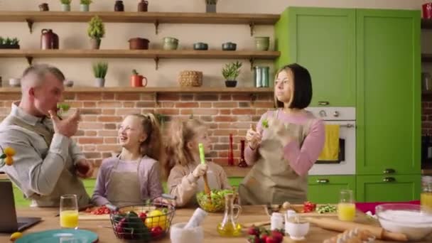 有两个小孩的大家庭白人女孩一起准备健康的晚餐 全家都在厨房里用蔬菜和沙拉做健康的食物 — 图库视频影像