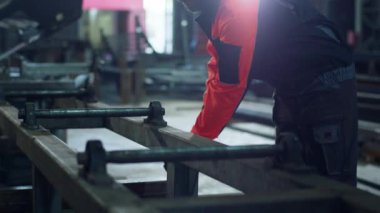 Büyük endüstriyel fabrika işçisi bir metal alır ve ağır bir makineyle güvenlik ekipmanı taktığı metali keser..