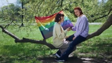 Kameranın önünde kısa saçlı lgbt bayrağını tutan ve kameranın önüne atlayan bayan doğanın ortasında çok mutlu. 4k