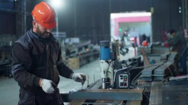 Karizmatik profesyonel demirci endüstriyel fabrikada çok çalışıyor. Metali kesmek için ağır makineler kullanıyor. Emniyet gözlüğü ve miğfer takıyor..