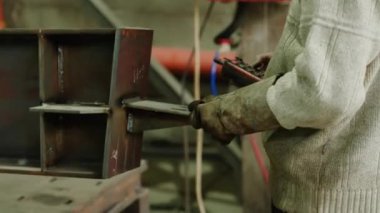 Metal ürünleri taşımak için özel bir makine kullanan endüstriyel demirci koruyucu eldiven ve ekipman takıyor..