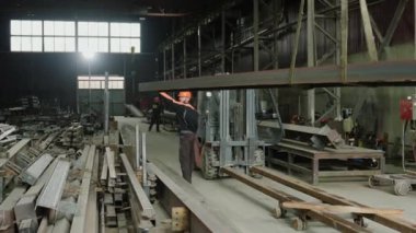 Güvenlik teçhizatı ve miğferli beyaz fabrika işçisi metali endüstriyel bir makineyle kesmek için hazırladı..