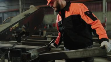 Kamera önünde üretim bölgesindeki endüstriyel fabrikada Kafkas karizmatik fabrika işçisi ağır endüstriyel makineler kullanarak metali kesiyor..
