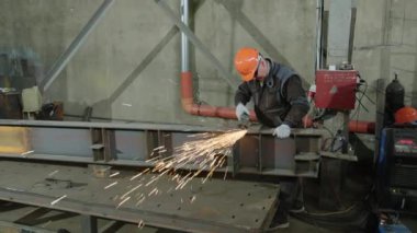 Endüstriyel fabrikada güvenlik ekipmanlarıyla kaynak yapan kaynak makinenin önündeki metali uçuruyor..