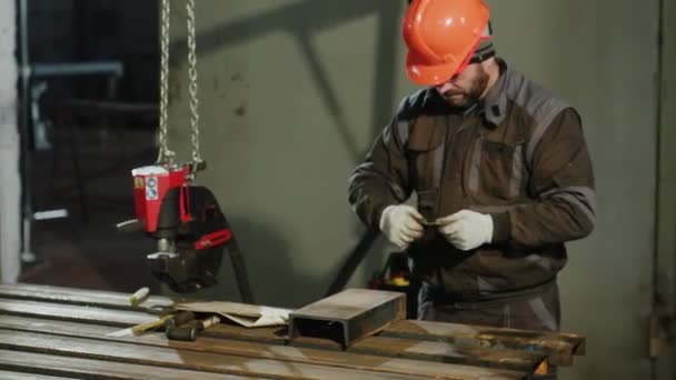在金属制造厂工作的专业铁匠 他测量金属的尺寸 佩戴安全设备和安全帽 — 图库视频影像