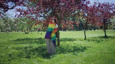 Kameranın önünde doğada iyi görünümlü karizmatik Igbt kadını lgbt gökkuşağı bayrağını al ve kendine sarıl ve kendini rahat hisset..