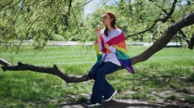 İyi görünümlü lgbt bayan ağaç dalında otururken biraz sabun köpüğü yapar ve dışarıda eğlenir..