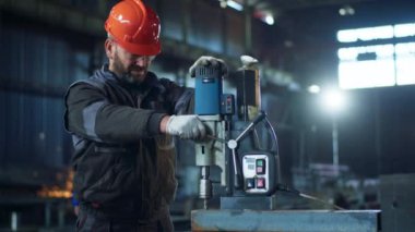 Kameraya yakın çekim yaparken fabrikada çalışan bir demircinin özel bir makineyle metali kestiğini gösteriyor..