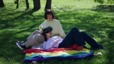 Güzel ve karizmatik lezbiyen çift parkta piknik yapıyor. Sanal gerçeklik gözlüklerini alıp oyun oynuyorlar ve birlikte vakit geçiriyorlar. 4k