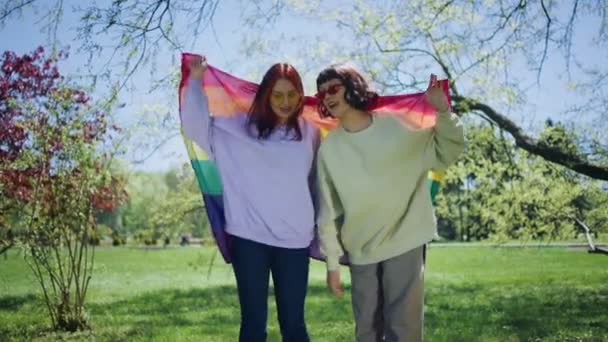 カメラの前でカリスマ的な2人の女性がLgbtの旗を踊り 一緒に楽しんでいる日を一緒に楽しむ — ストック動画