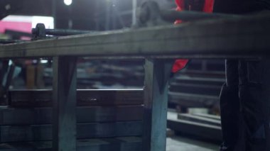 Endüstriyel fabrika işçisi bir parça ağır metal alır ve özel makinelere taşır..