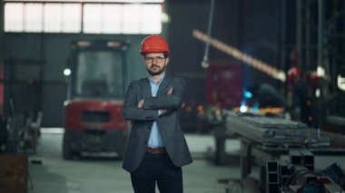 Üretim fabrikasında kameranın önünde poz veren çekici genç girişimci güvenlik kaskı takıyor ve el ele tutuşuyor. 4k