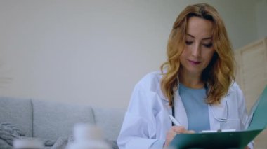 Kameraya yakın beyaz üniformalı güzel GPS doktoru hastaya iyileşmek için hangi hapları alması gerektiğini açıklıyor. Hastaya bakıyor ve gülümsüyor. 4k