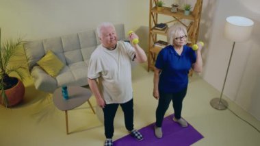 Evde karizmatik bir çiftin oturma odasının ortasında egzersiz yaparken yoga minderinin başında durup egzersizin bitiminden sonra birbirlerine beş dakika veriyorlar. 4k