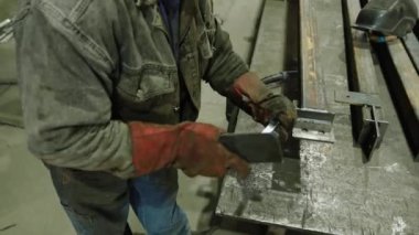 Üretim alanında metal üretiminde çalışan kaynakçı, üretim bölgesindeki metal işlerinde çekiç kullanıyor..