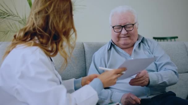 Дома Пожилому Пациенту Назначают Медосмотр Врач Разъясняет План Лечения Мило — стоковое видео