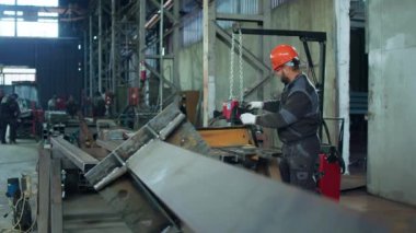 Bir endüstriyel fabrikada iş süreçlerinin videosunu çeken işçilerin çoğu ağır makineler kullanıyor ve güvenlik ekipmanları takıyorlar..