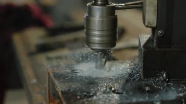 Metal fabrikası, metal parçasında delikler açan ağır bir endüstriyel makinenin görüntülerini yakalıyor..