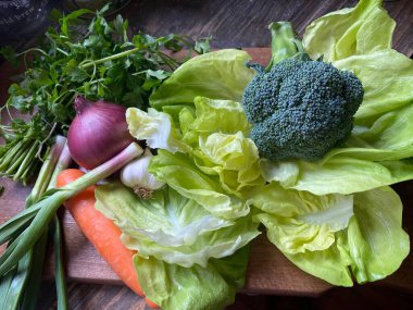 vegetables on a wooden table with fresh herbs and greens