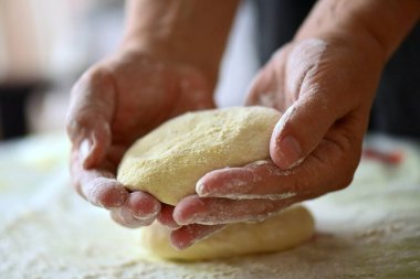 Mutfaktaki masada ekmek ile ev yapımı hamur yapan kadınların yakın plan görüntüsü.