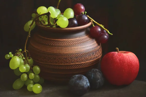 在木制桌子上挂着一筐葡萄和苹果 过着平静的生活 — 图库照片