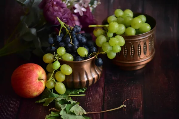 深色桌子上的铜碗里有一束红熟的葡萄 新鲜的水果在篮子里 健康食品 — 图库照片