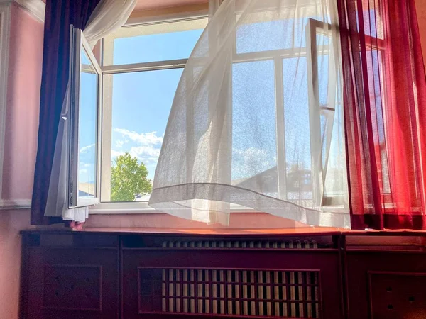 Perdeli ve kırmızı perdeli bir pencere.