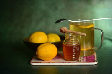 Cam kavanozda bal, kaşıkla ve kasede limonla.