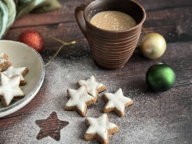 Noel kurabiyeleri, bir fincan kahve ve ahşap arka planda Noel süsleri.