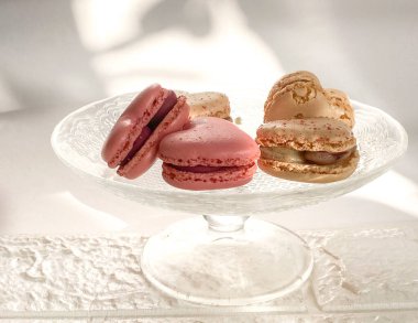 Üç farklı renkte badem kurabiyesi olan cam bir tabak.