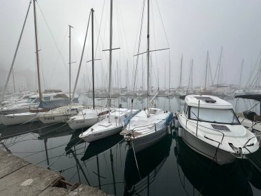 Sis altındaki bir rıhtımda park etmiş teknelerin yakın çekim görüntüleri.